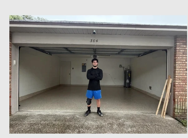 Open garage with completed speckled epoxy-coated floor and contractor standing in center